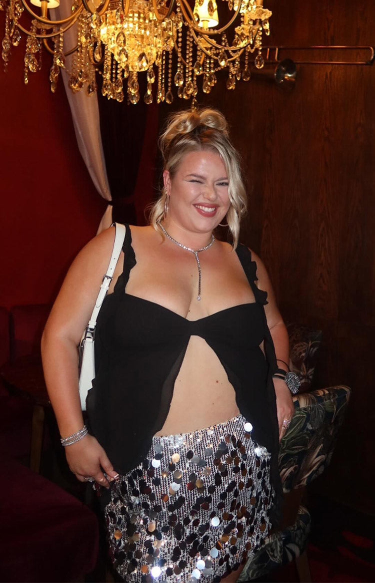 Front view of a silver sequin mini skirt with large reflective round sequins and a fitted silhouette