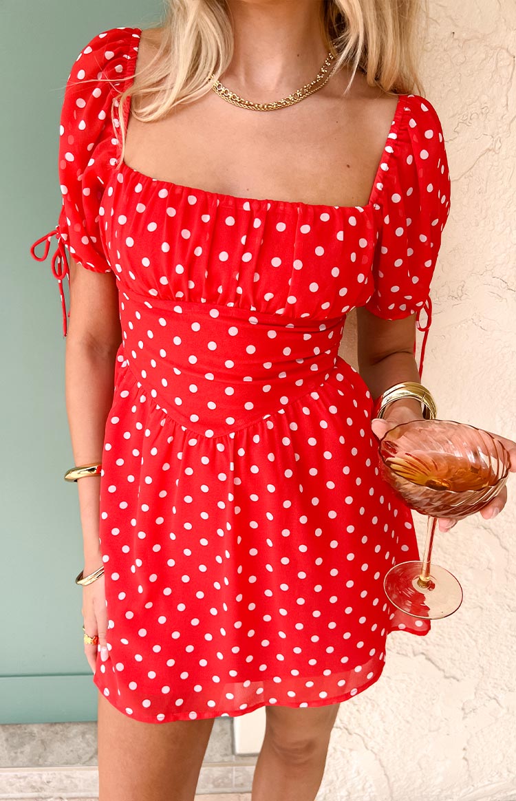 Red polka dot mini dress with a square neckline, shirred bust, short puff sleeves with ties, and a fitted V-waist