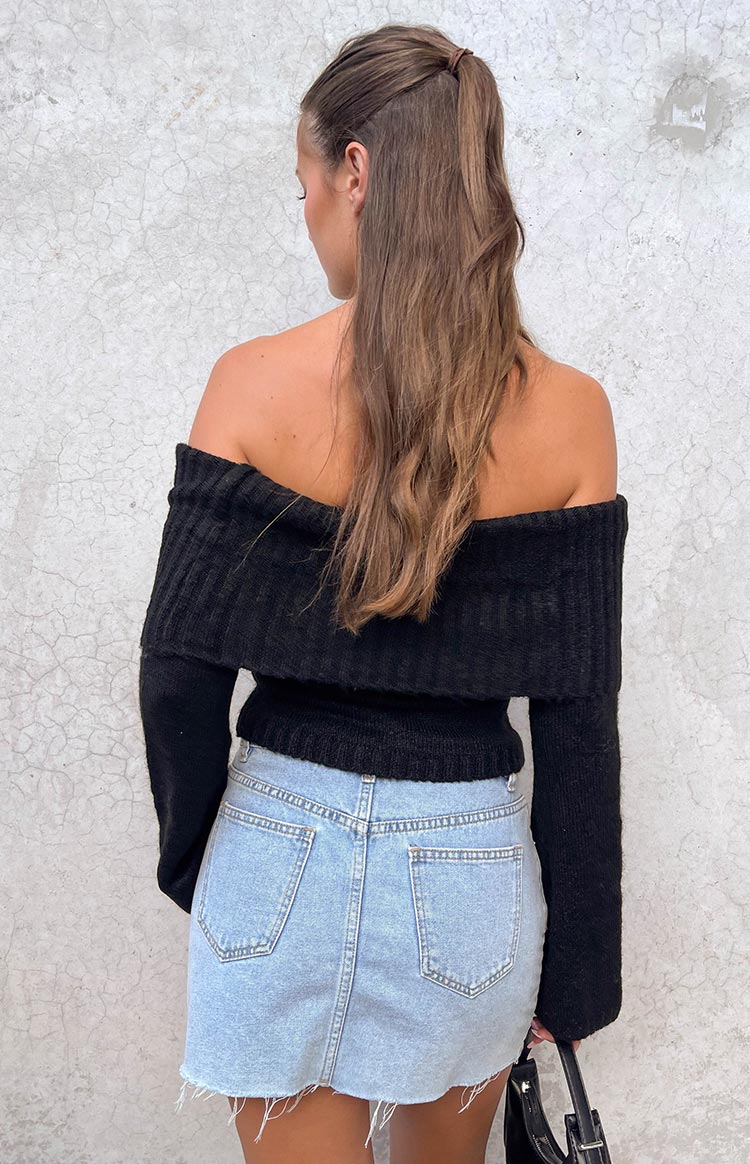 Rear view of a black off-shoulder sweater with a wide ribbed fold-over neckline and fitted hem