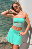 Side view of the teal lace mini skirt with a ruched elastic waist and front tie detail