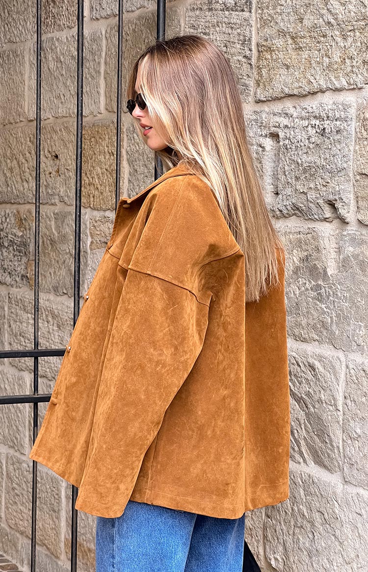 Side profile of a tan suede oversized jacket, highlighting the soft texture and relaxed, dropped shoulder fit