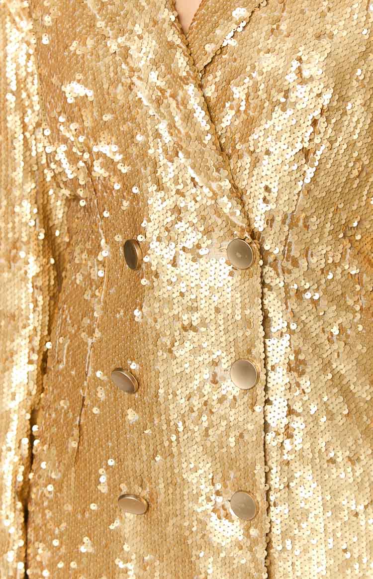 Close-up showing the gold sequin texture and double-breasted gold buttons on the blazer mini dress