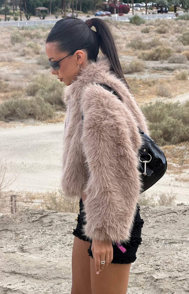 Side view of a light brown faux fur jacket with shaggy texture and cropped length