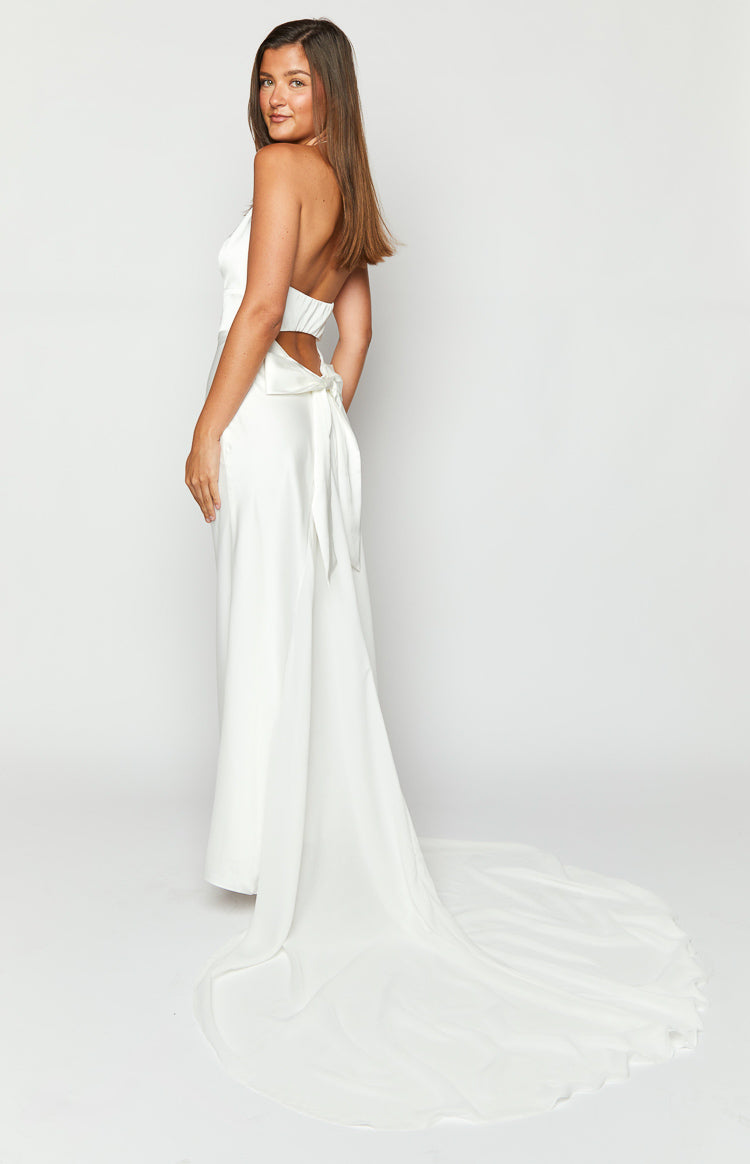 Rear-side view of a white halter neck maxi dress with an open back, tie detail, and long flowing train