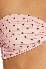 Close-up of the twisted front and ruched fabric of the pink polka dot strapless bikini top