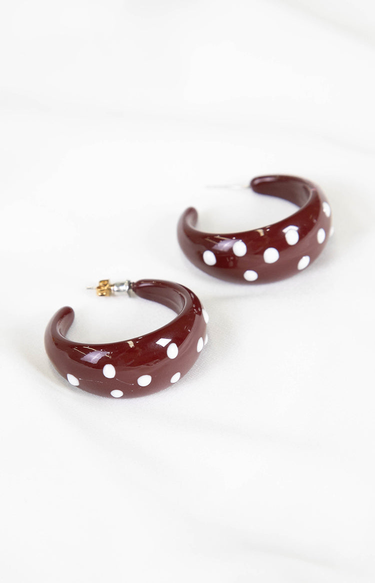 Pair of burgundy chunky hoop earrings with white polka dots, showing the post-back closure