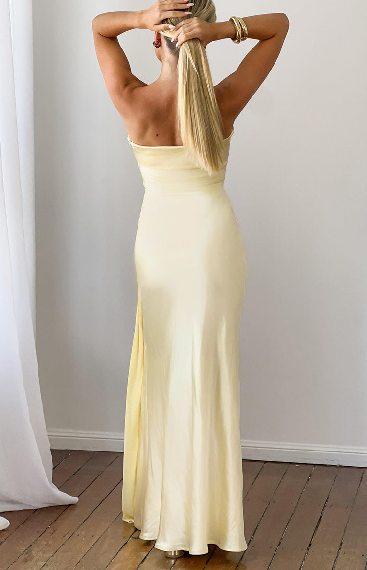 Rear view of a yellow satin strapless maxi dress with a flowing skirt and subtle side slit