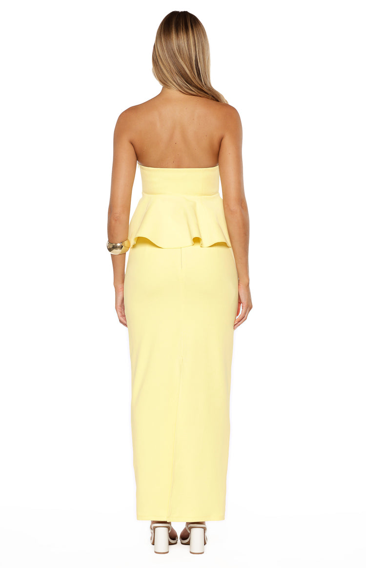 Back view of the yellow crepe strapless top, highlighting the fitted bodice and ruffled peplum waist