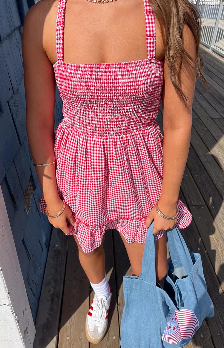 Close-up of the red and white gingham mini dress showing the smocked bodice, gathered skirt, and ruffled hem