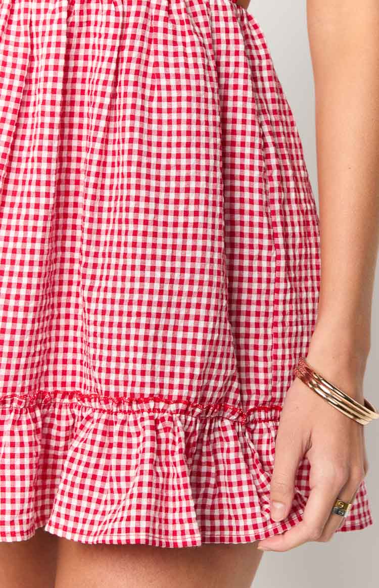 Close-up of the red gingham mini dress's gathered hemline with a small ruffle detail