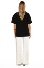 Rear view of ivory satin straight leg pants with delicate lace trim at the hem