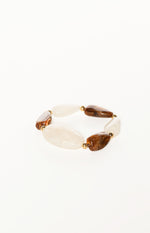 Angled view of an elastic bracelet with alternating brown marbled and milky white resin beads separated by gold spacers