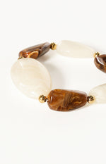 Close-up of the brown and creamy white marbled resin beads with gold-tone spacers on an elastic bracelet