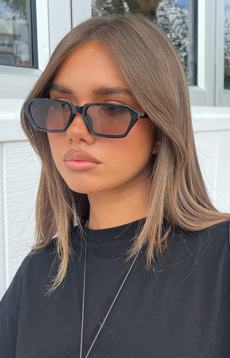 Close-up of black olive square frame sunglasses with dark tinted lenses and subtle cat-eye detail