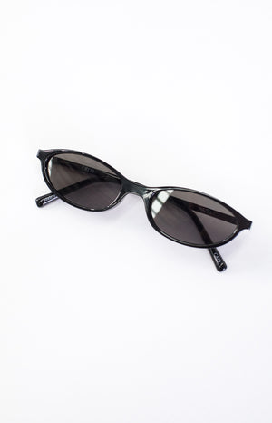 Angled overhead view of black cateye sunglasses with "otra" on left lens and "HAZEL" on right lens, "CATE3" on arm