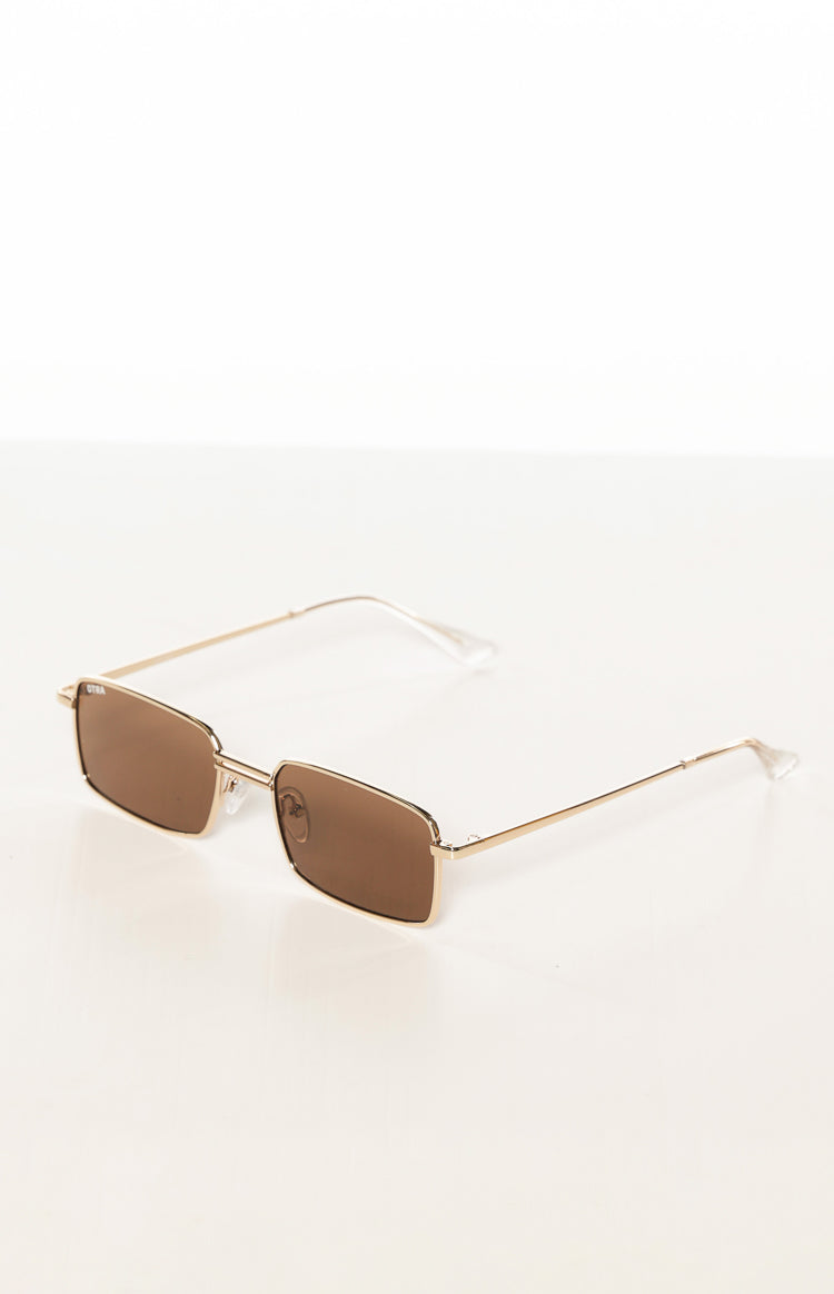 Angled view of gold metal frame sunglasses with brown square lenses and extended arms showing clear tips