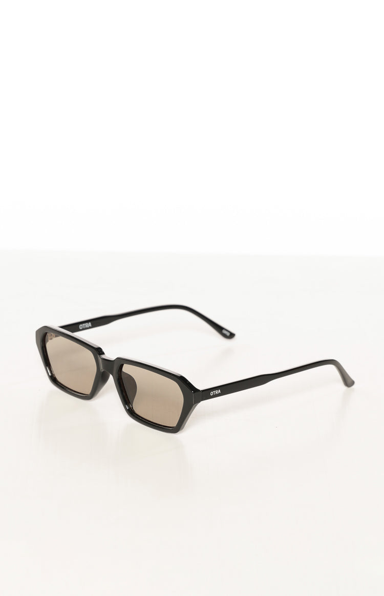 Angled view of black hexagonal-square frame sunglasses with olive tinted lenses and OTRA logo on arms