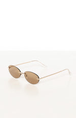 Angled view of brown oval sunglasses with thin gold metal frames, bridge, and clear temple tips