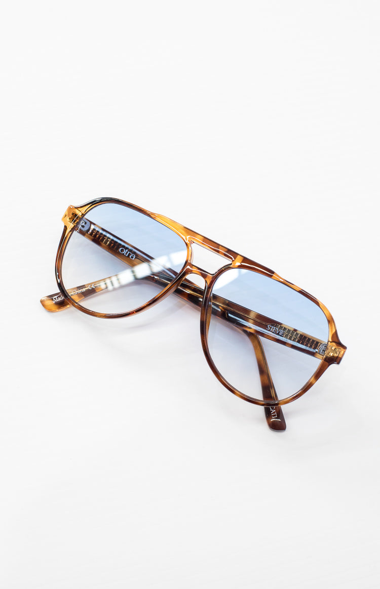 Tortoiseshell aviator sunglasses with light blue gradient lenses, Otra logo on left lens and Stevie on right temple