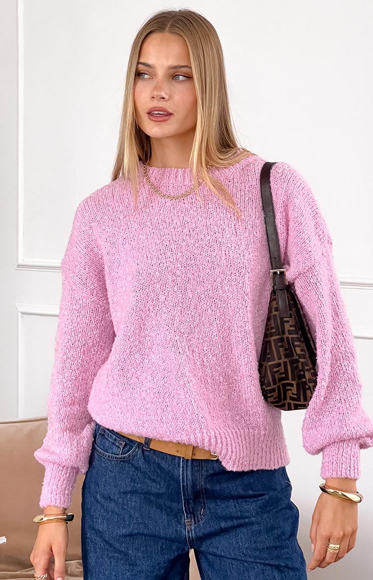 Close-up of a pink knit sweater showing the textured yarn and relaxed long sleeves with ribbed cuffs