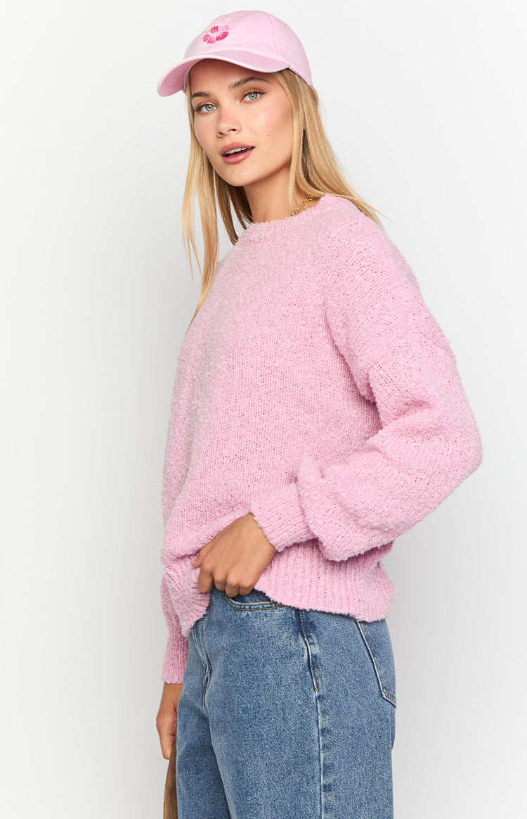 Side view of a pink knit sweater with a textured, fluffy appearance, relaxed fit, and long ribbed sleeves