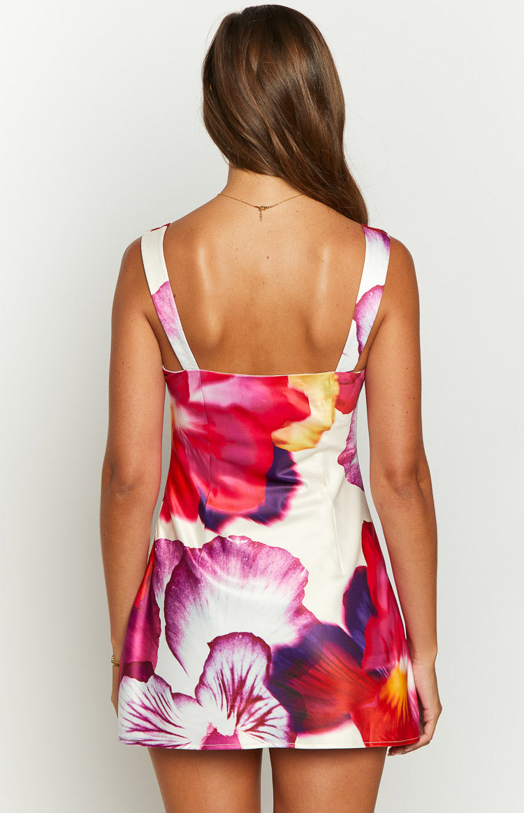 Rear view of a white mini dress with large pink, purple, and red pansy floral print and wide shoulder straps