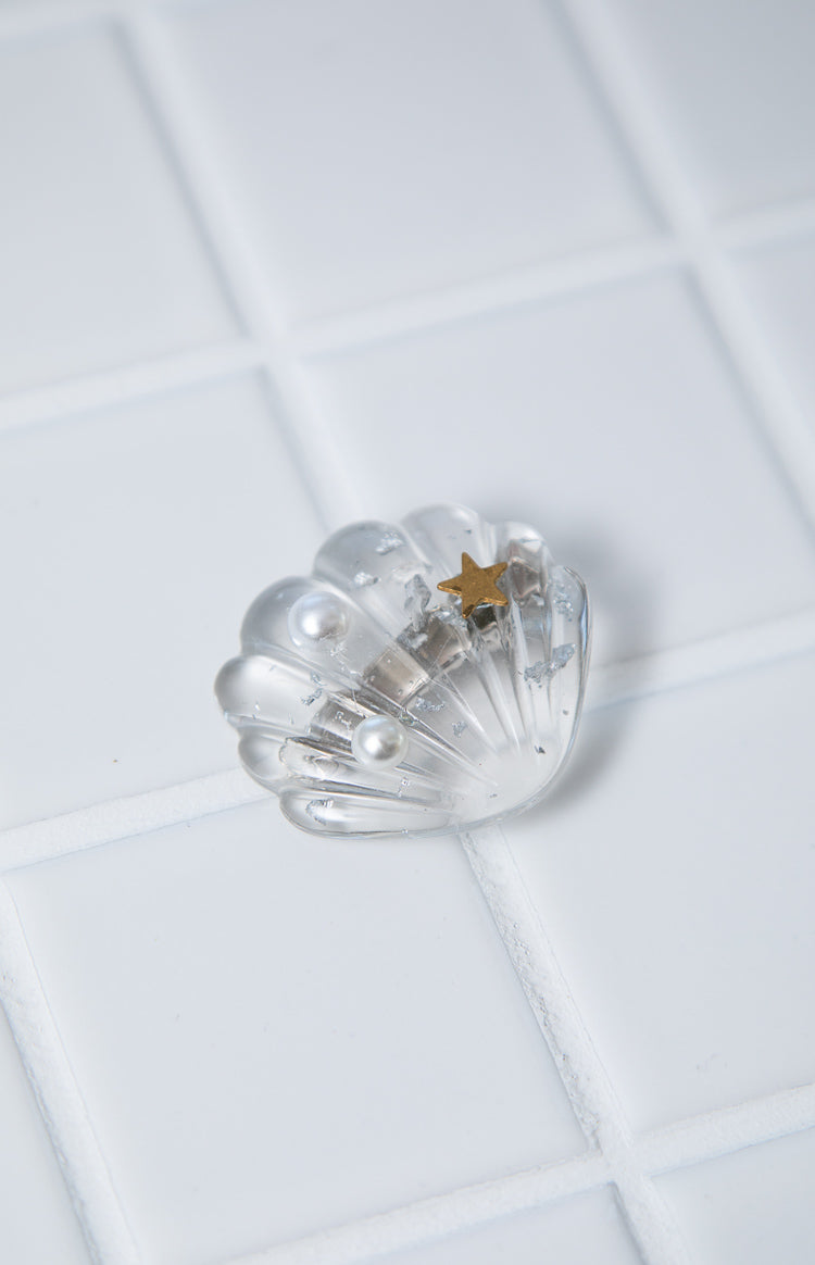 Clear shell hair clip with two white pearls, a gold star, and silver flakes embedded inside