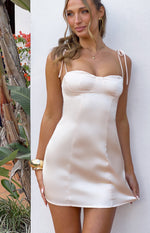 Cream satin mini dress with a sweetheart neckline, bustier cups, and delicate tie-up spaghetti straps