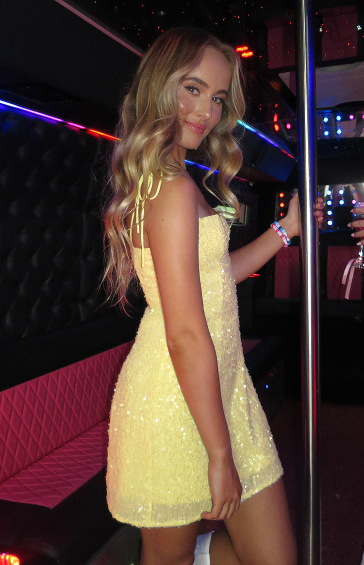 Side view of a yellow sequin mini dress with tie-up spaghetti straps and an A-line fit
