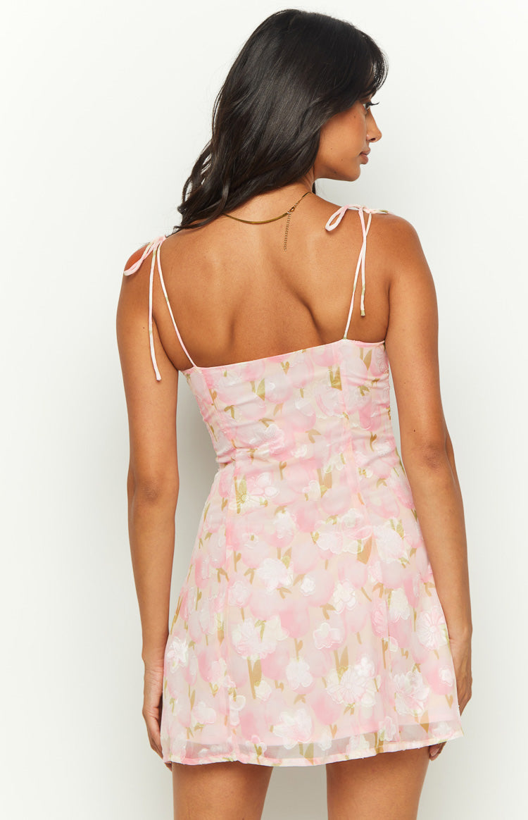 Rear view of a pink floral mini dress with tie-up spaghetti straps and a square back