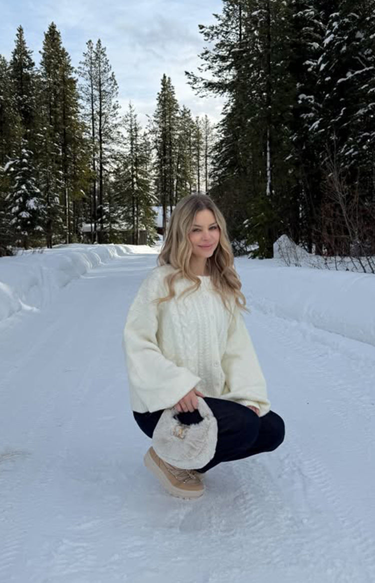 Cream cable knit cardigan with a crew neck, relaxed fit, and visible front buttons