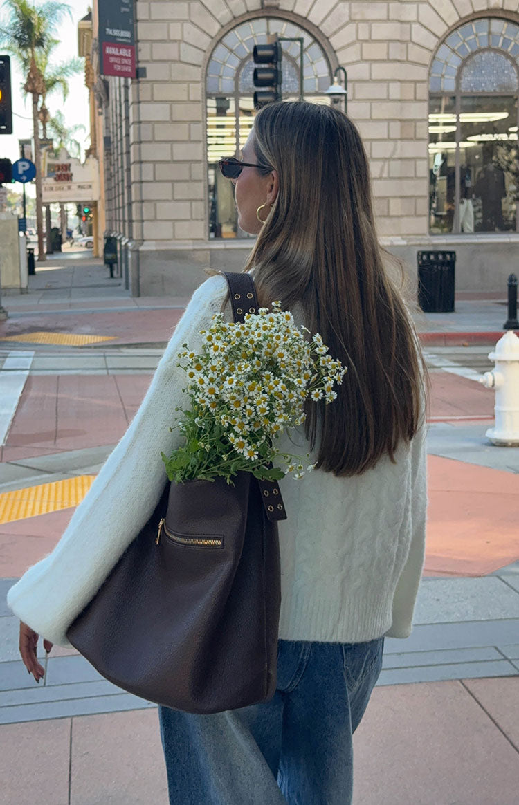 Back view of a cream cable knit cardigan, showing the textured knit pattern and relaxed long sleeves