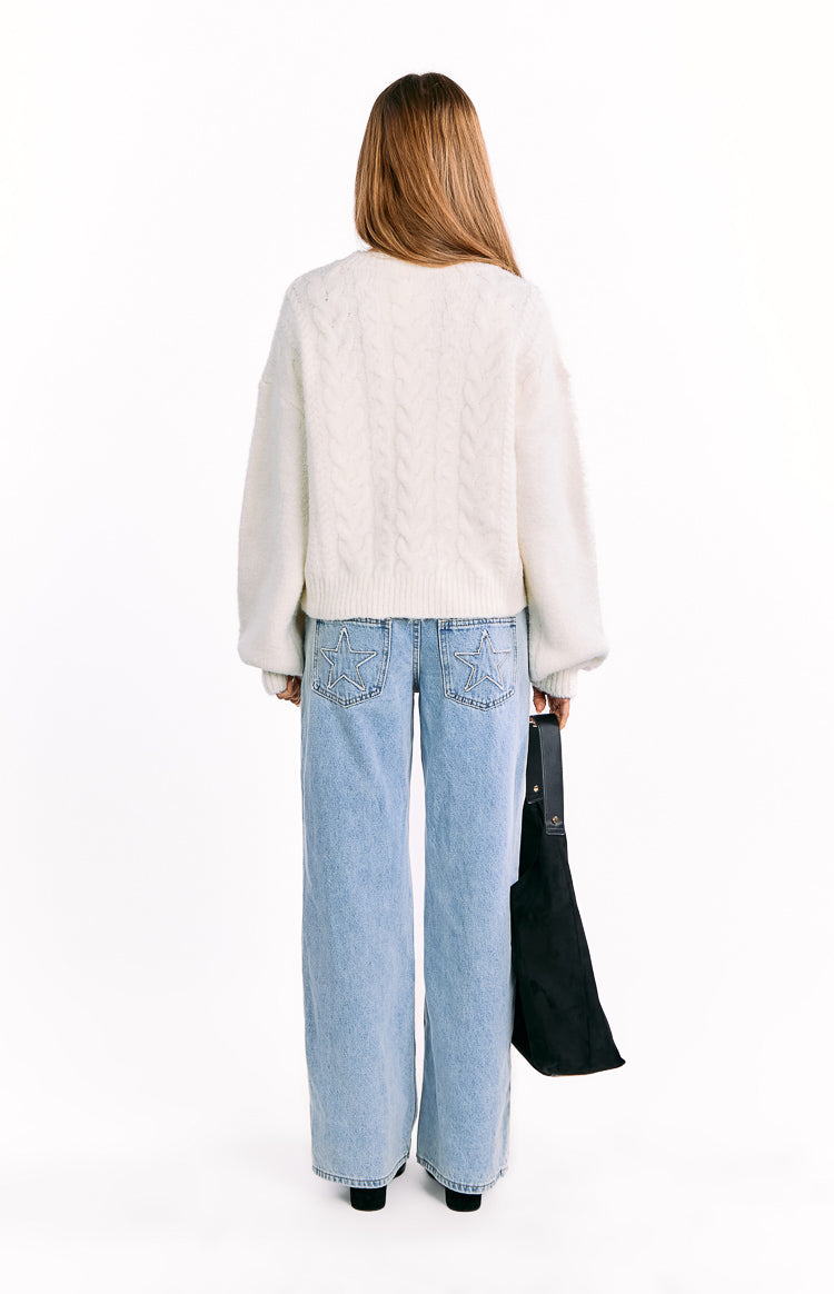 Rear view of a cream cable knit cardigan with a chunky cable knit pattern and dropped long sleeves