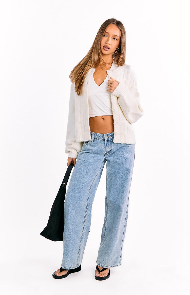 Cream cable knit cardigan worn open, showing the cropped length and ribbed hem