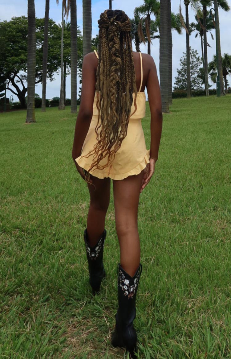 Rear view of petal yellow shorts with an elasticated waist and a ruffled hem