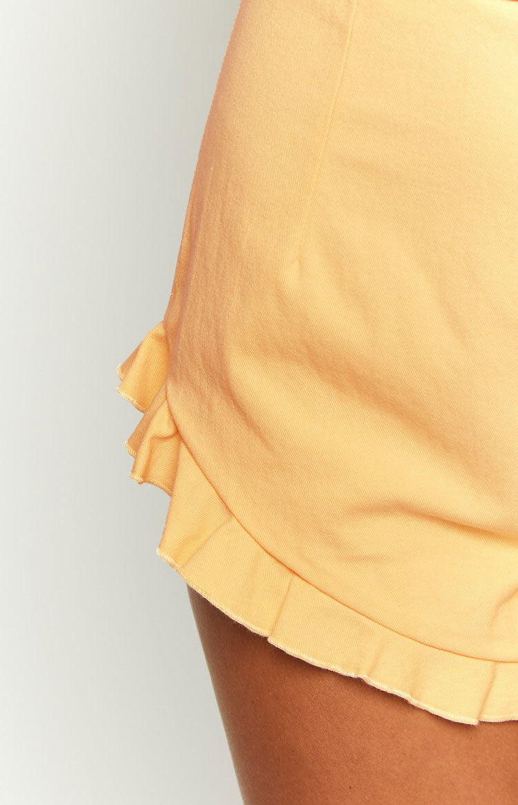Close-up side view of the layered ruffled hem on petal yellow shorts