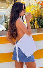 Side view of the white linen blend top showing the open back and waist tie detail