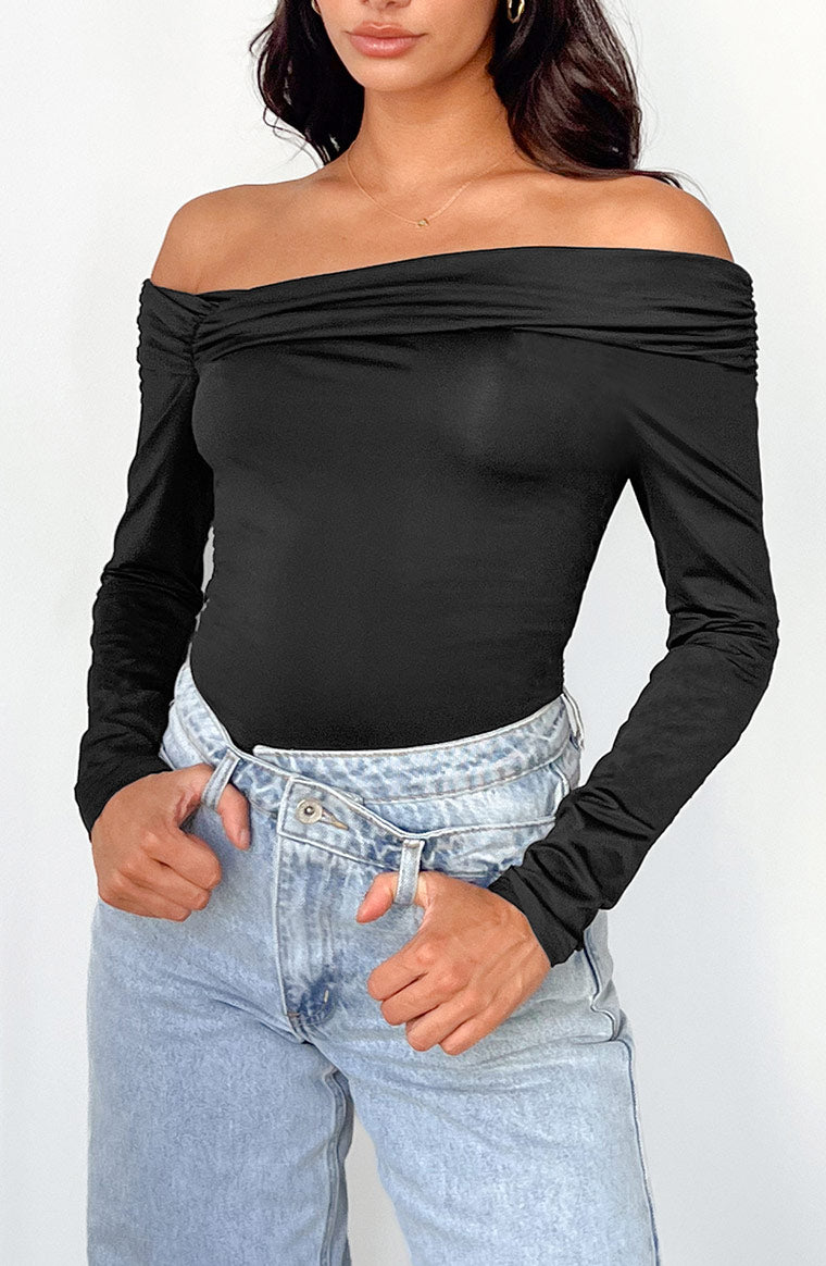 Close-up of the black off-shoulder bodysuit showing the draped neckline and ruched long sleeves