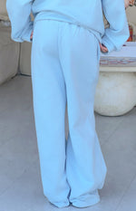 Rear view of blue mid rise slouch fit trackpants, showing the full wide leg silhouette
