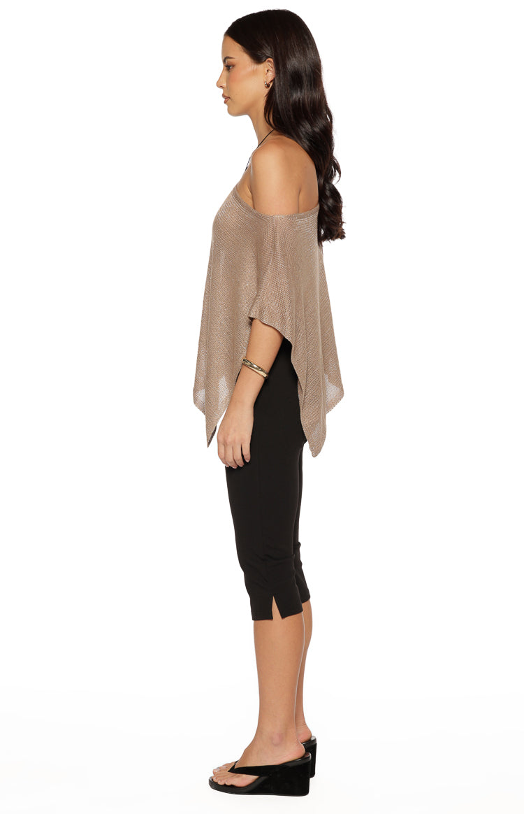 Side view of the metallic knit poncho showing the off-shoulder neckline and draped, flowing silhouette