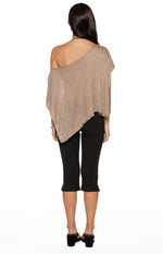 Rear view of a light brown metallic knit poncho with an off-shoulder neckline and asymmetrical draped hem