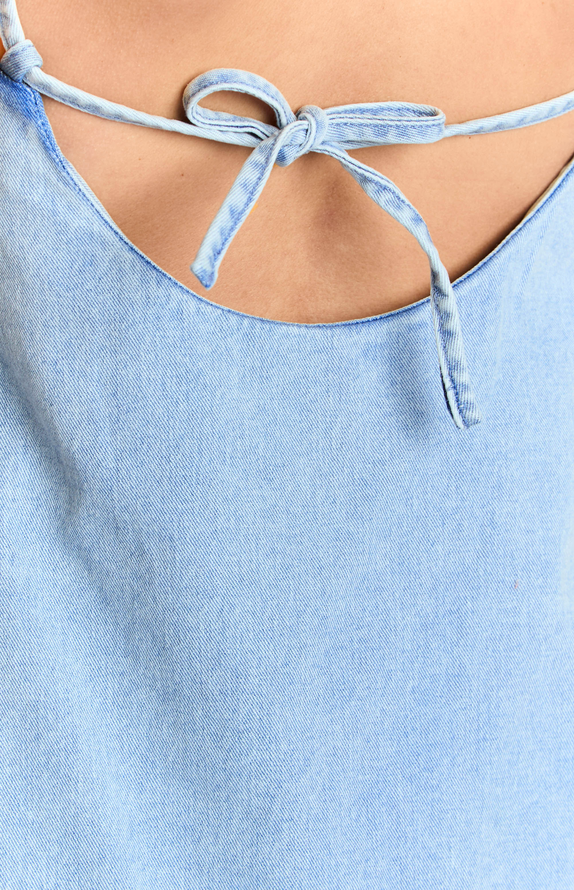 Close-up of the tied bow straps at the back of the mid wash denim dress