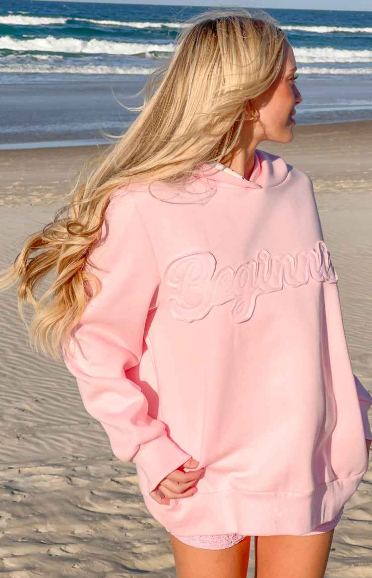 Side view of a pink hoodie with an embroidered "Beginning" logo on the front and ribbed cuffs