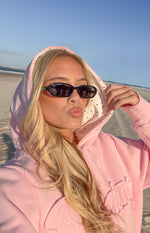 Close-up of the pink hoodie showing the white hood lining with black polka dots and ribbed cuff