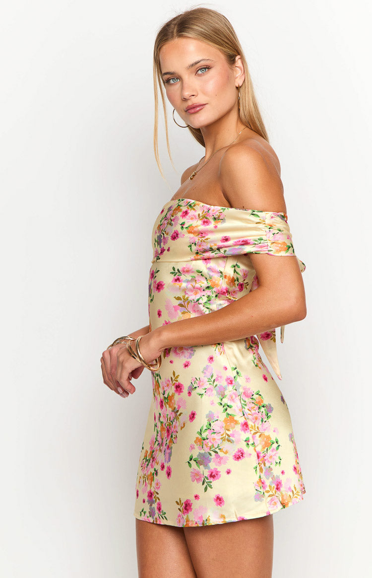 Side view of a primrose yellow floral mini dress with ruched off-shoulder sleeves and a side tie detail