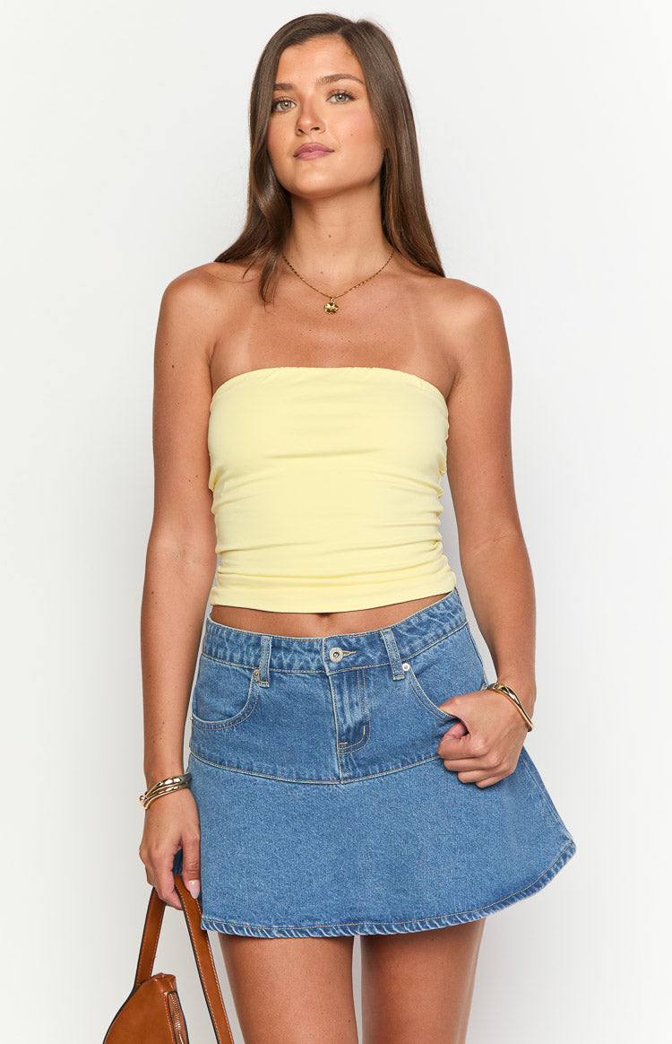 Front view of a mid-wash denim mini skirt with a fitted waist, belt loops, and a slight A-line flare