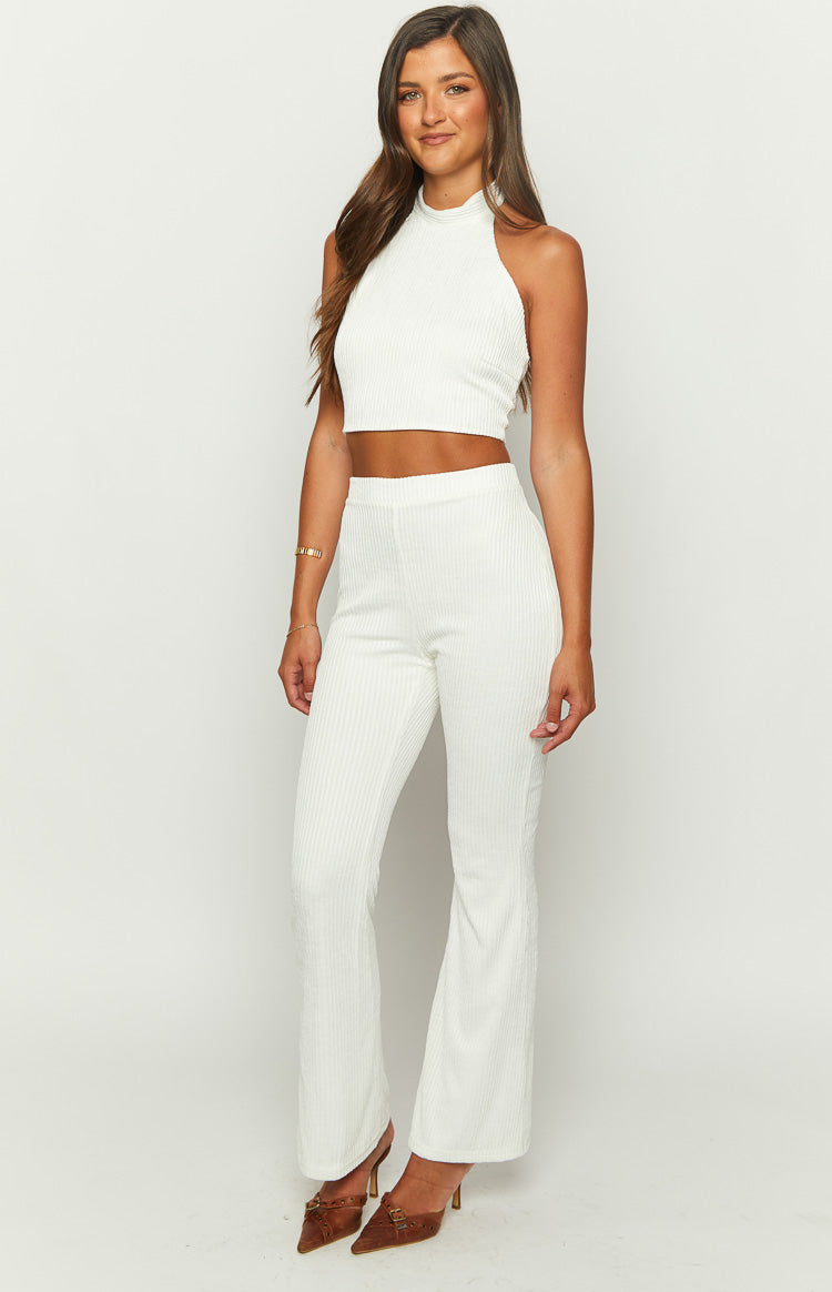 Side view of white ribbed pants with a high waist and a gentle flare from the knee down