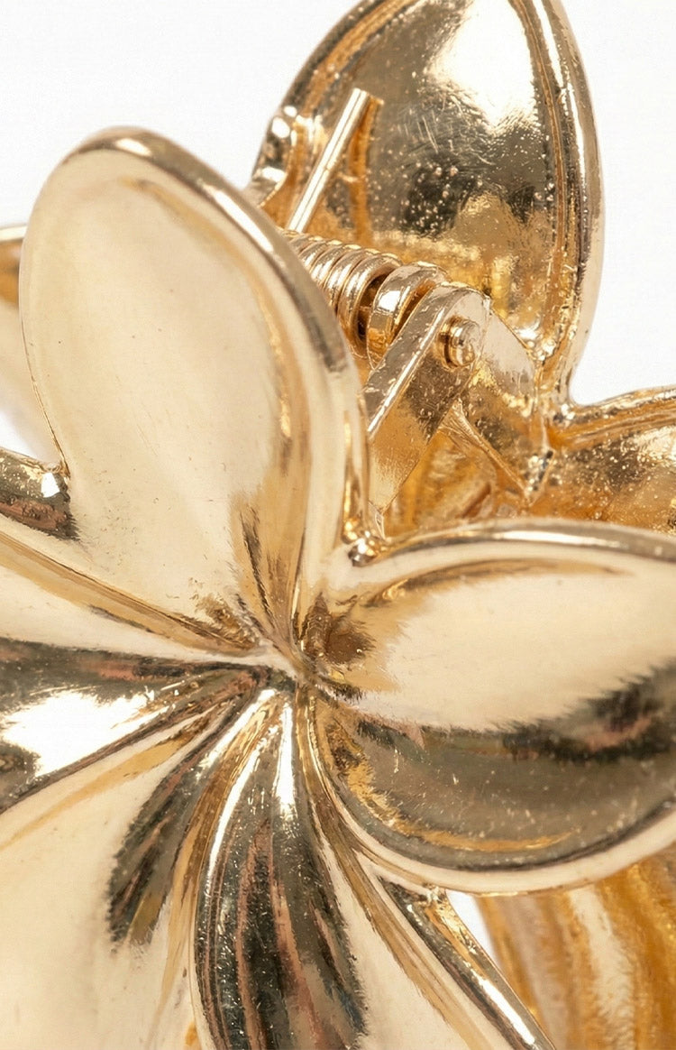 Close-up of the gold metal flower claw clip showing the spring mechanism and shiny petal texture