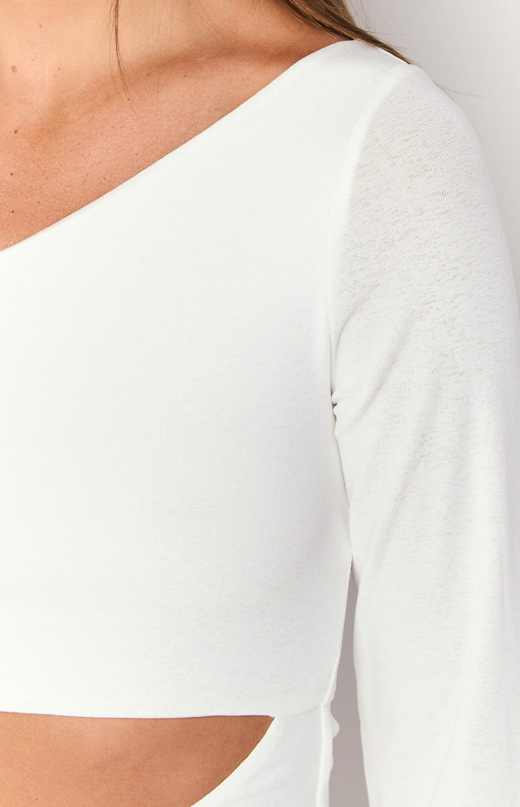 Close-up of the white knit fabric, showing the one-shoulder neckline, long sleeve, and waist cutout detail of the mini dress