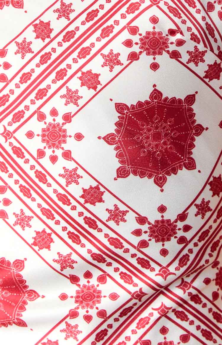 Close-up of the red and white tile print fabric with geometric and floral motifs on a maxi dress